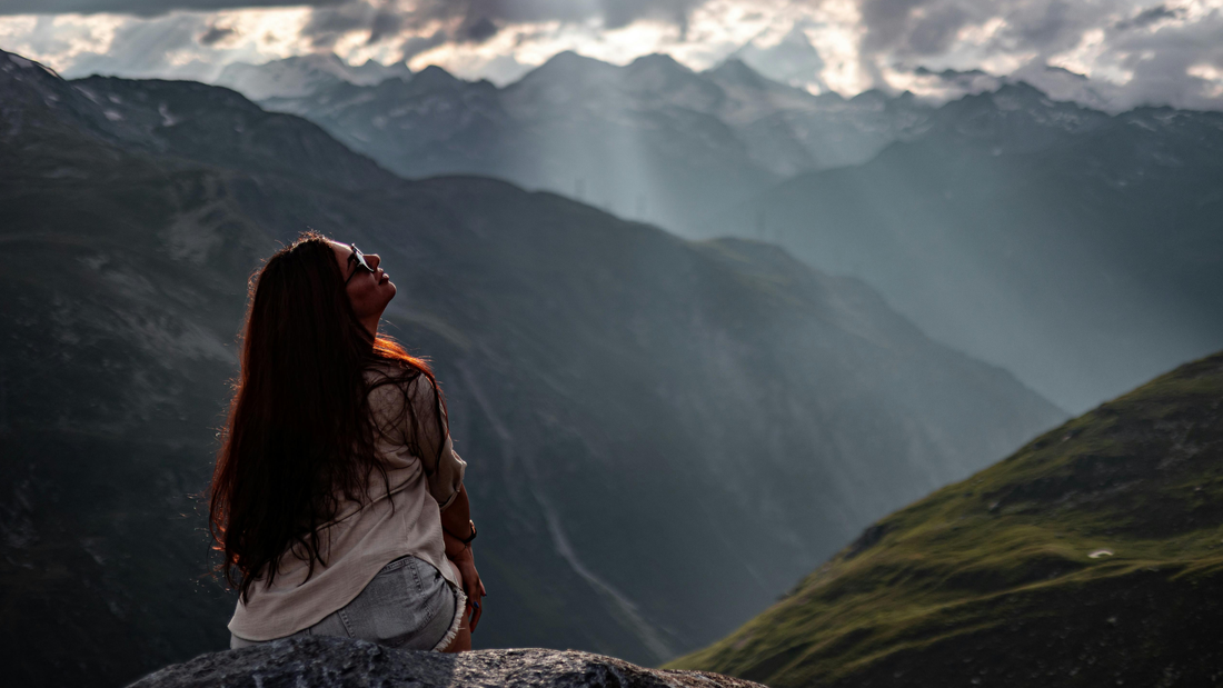 Woman sitting among mountains pondering, 'Who am I in Christ?'