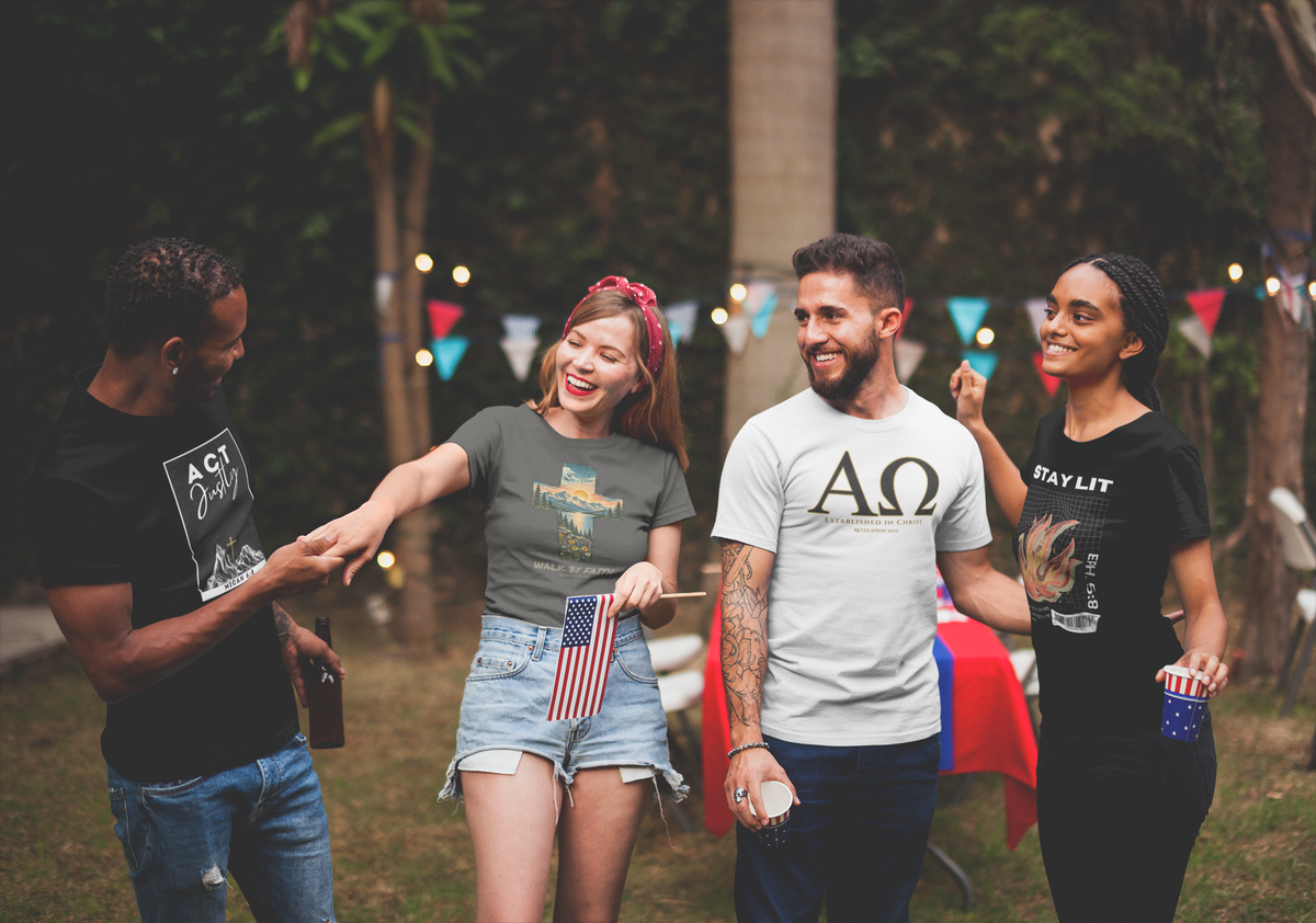 Four friends celebrating outdoors at a party, wearing Christian  graphic t-shirts. One man wears a black bible verse t-shirt with a white graphic, another wears a gray  women's faith t-shirt with a colorful graphic, a third wears a white faith based  t-shirt with a Greek letter design, and the fourth wears a black Christian graphic t-shirt with a fire graphic.