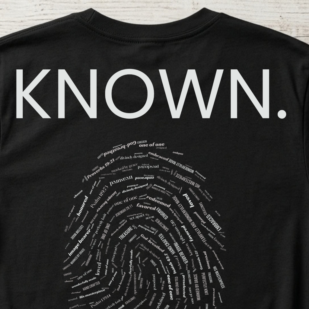 Close up details of the Christian youth Shirt that says Known above a white fingerprint inlaid with words of affirmation from God.