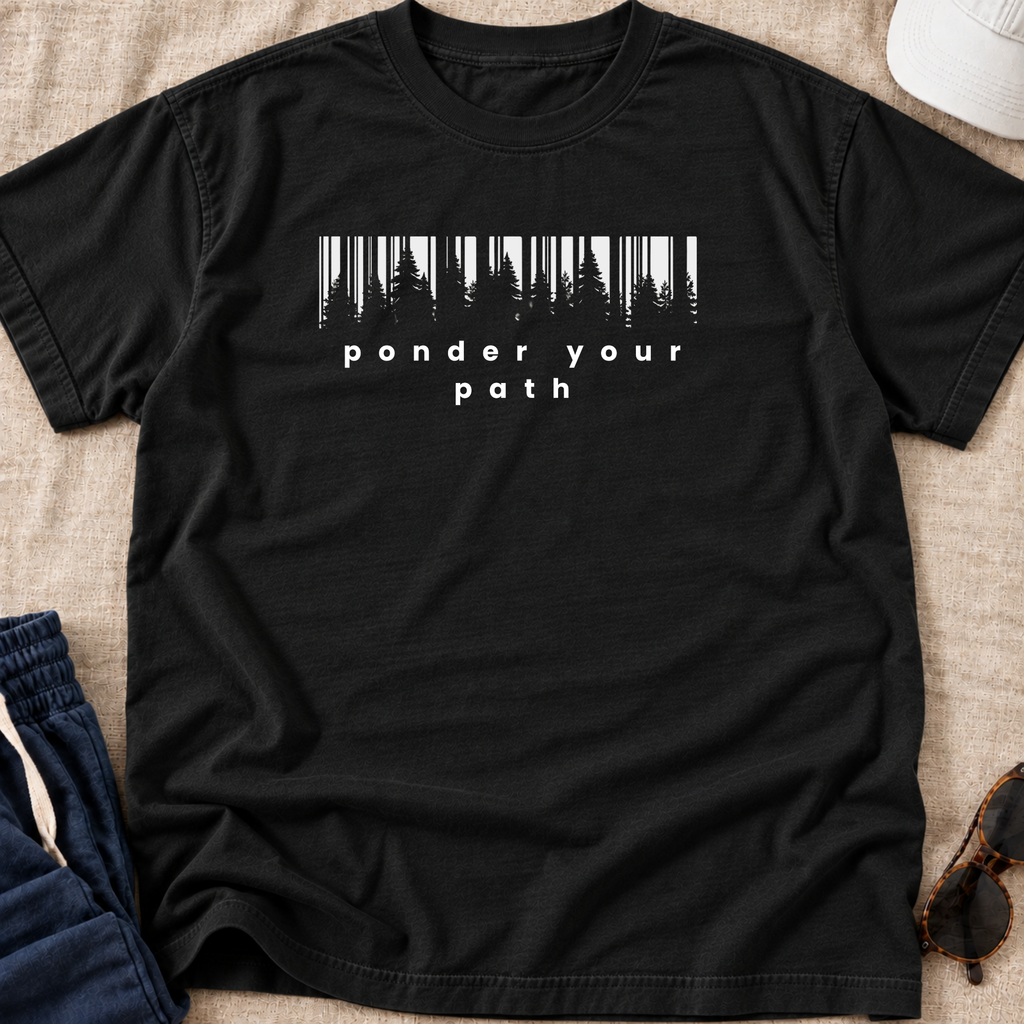 A black short-sleeve crewneck t-shirt laid flat on a beige textured fabric background. The shirt features a white graphic print of vertical tree silhouettes above the words 'ponder your path' in a clean sans-serif font.