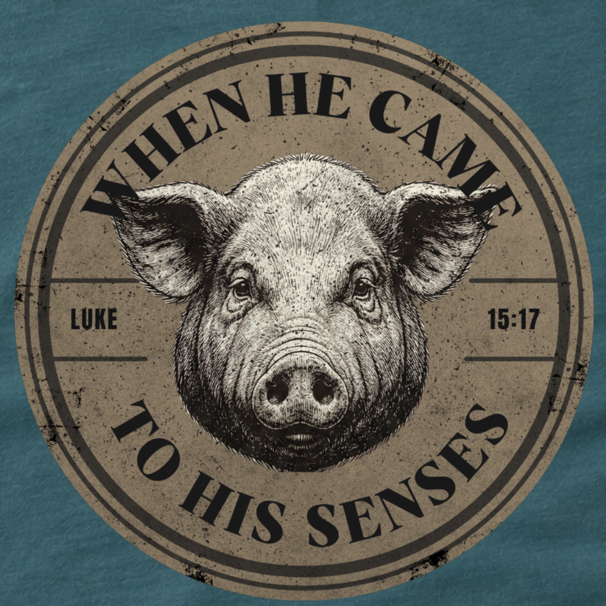 A circular vintage-style graphic print featuring a detailed illustration of a pig's face in the center, with the text 'WHEN HE CAME TO HIS SENSES' and 'LUKE 15:17' on a distressed tan background, shown on a teal-blue fabric surface.