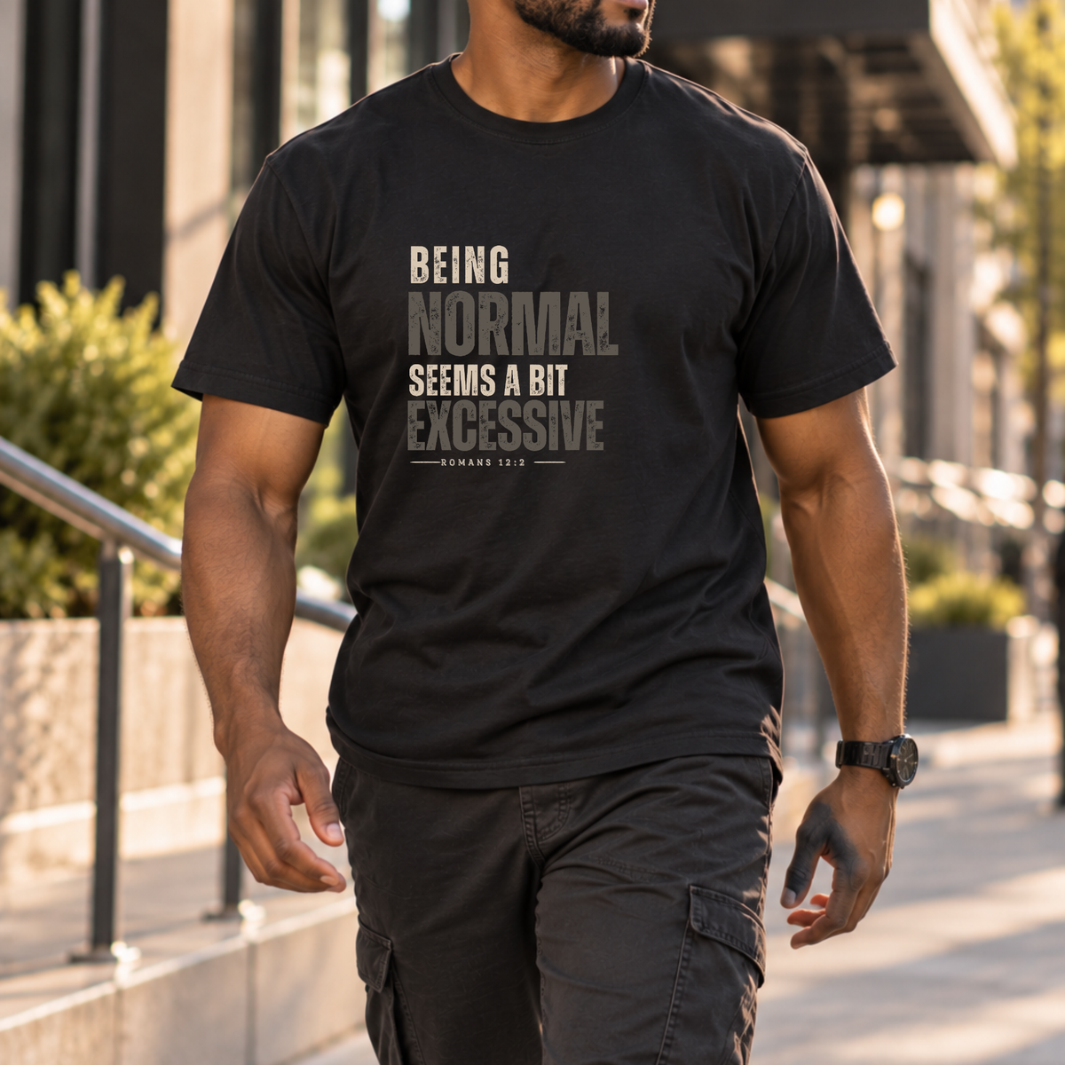 a man walking down a sidewalk wearing a black shirt that has monochrome black and gray lettering that says 'being normal seems a bit excessive' 'Romans 12:2"