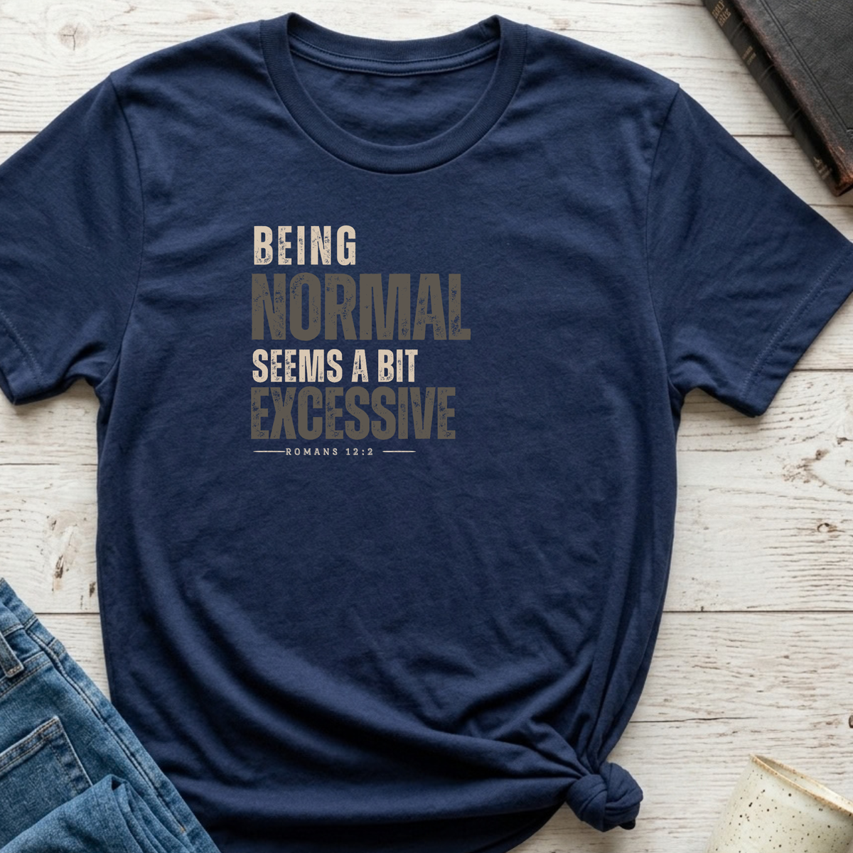 a navy shirt that has monochrome black and gray lettering that says 'being normal seems a bit excessive' 'Romans 12:2"