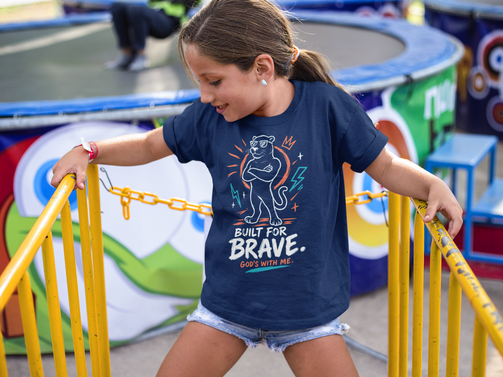 A young girl wearing a navy blue Christian graphic t-shirt by SeedSowerGraphics with a cartoon panther and the text 'BUILT FOR BRAVE. GOES WITH ME.