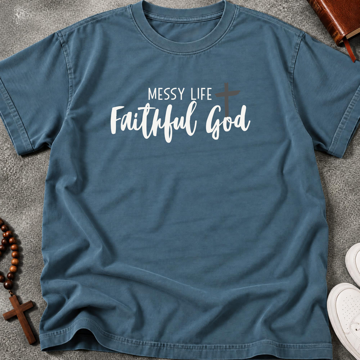 Steel Blue shirt surrounded by a bible, cross, and white sneakers with the words 'messy life faithful god' in white lettering across the shirt.