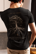 A man viewed from behind wearing a black Christian graphic t-shirt with a large graphic print on the back. The print features a tree of life with roots, the text 'BUILT ON CHRIST' at the top and 'WALKING IN HIM, ROOTED IN HIM, ESTABLISHED IN THE FAITH' at the bottom, and 'COL 2:7' on either side of the tree.