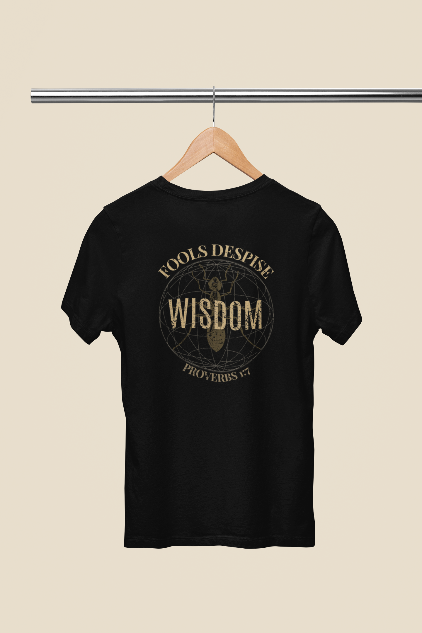 A black short-sleeve Christian graphic t-shirt hanging on a wooden hanger against a light beige background. The back of the shirt features a circular graphic with the words 'FOOLS DESPISE' and 'WISDOM'  'Provebers 1:7 in a distressed gold font.