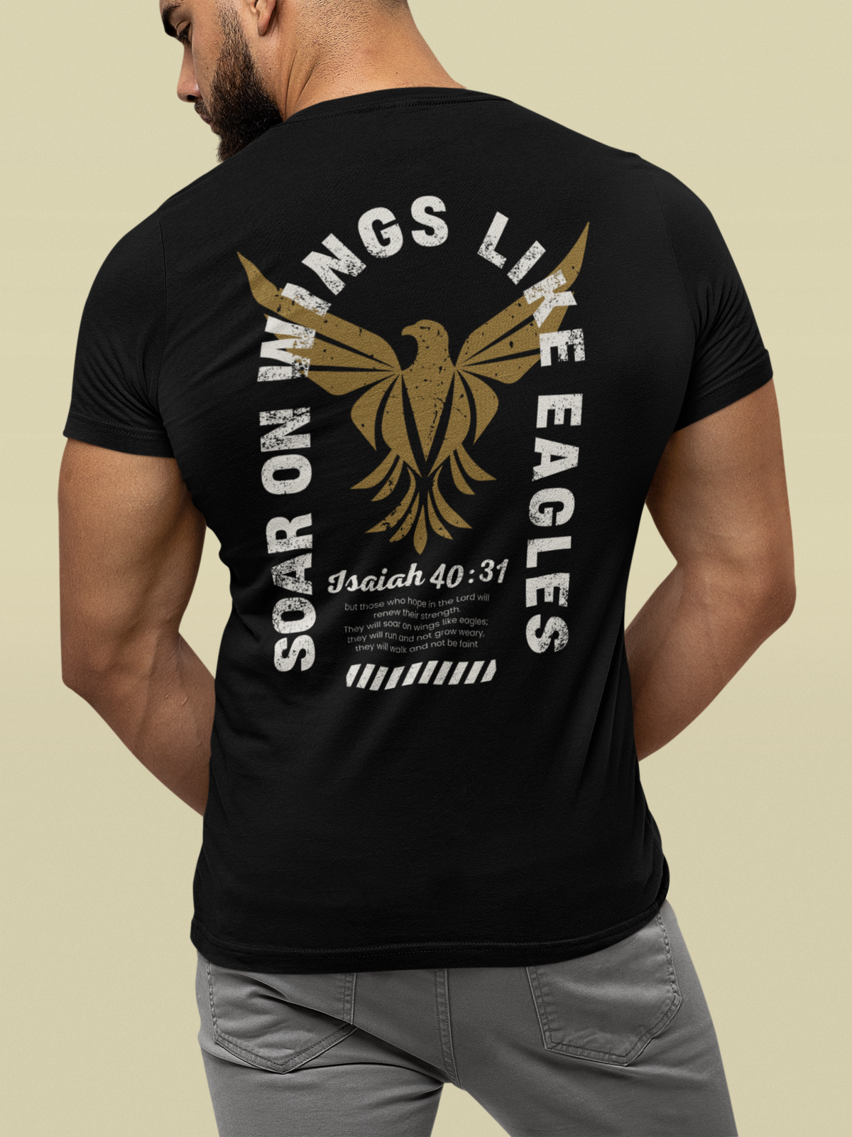 A man shown from the back wearing a black Christian graphic short-sleeve t-shirt with a large distressed graphic on the back. The graphic features a gold eagle, the words 'SOAR ON WINGS LIKE EAGLES' in white, 'Isaiah 40:31' in black, and a small white text block at the bottom.