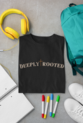 A folded black Christian graphic T-shirt with the words 'DEEPLY ROOTED' and a cross symbol across the chest, styled in a flat lay on a gray surface with yellow headphones, a teal backpack, a notebook, colored markers, and white sneakers.