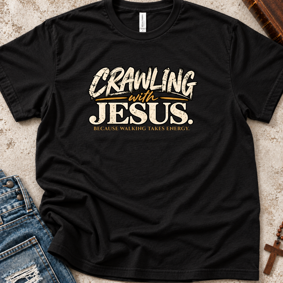 black Christian t-shirt by SeedSowerGraphics laid out amongst props with the saying 'crawling with jesus' because walking takes energy.