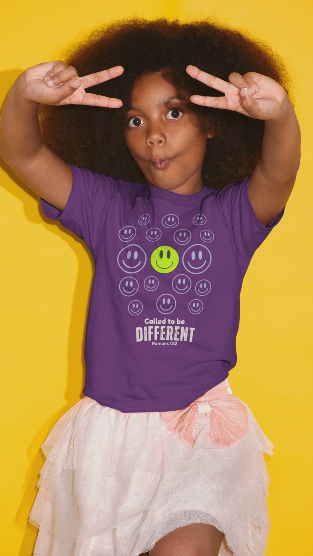 A young girl posing in multiple still images wearing a purple Christian graphic tshirt by SeedSowerGraphics with multiple smiley faces and one prominent green smiley with the words below it that says, "Called to be Different" 'Romans 12:2